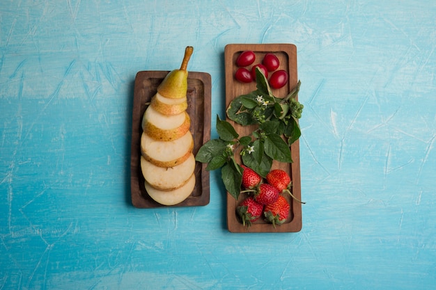 Fette di pere con fragole e gelsi in taglieri di legno al centro