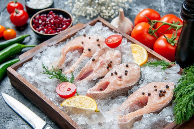 Fette di pesce crudo vista dal basso con fette di limone ghiaccio su ciotole di legno con semi di pemagranate sale marino sul tavolo