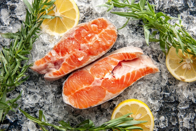 Fette di pesce fresco vista dall'alto con limone e ghiaccio sul tavolo scuro