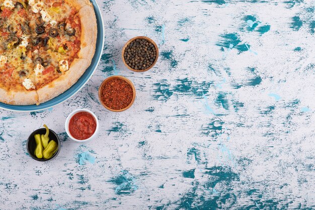 Fette di pizza calda con pepe in grani e polvere di pepe su uno sfondo di marmo.