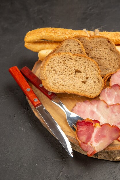 Fette di prosciutto fresco vista frontale con panini e fette di pane su spuntino scuro carne foto a colori pasto alimentare