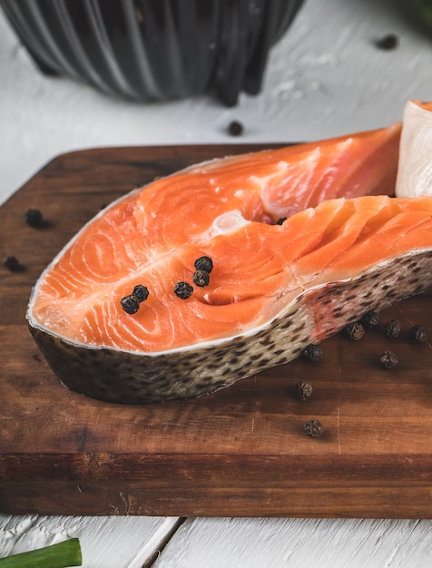 Fette di salmone con palline di pepe nero su una tavola di legno