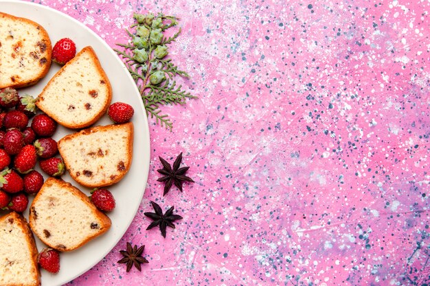 Fette di torta deliziosa vista dall'alto con fragole rosse fresche sulla torta scrivania rosa cuocere il biscotto di zucchero torta di colore biscotto dolce