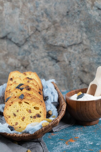 Fette di torta di sultanina su cesto di legno su asciugamano blu.