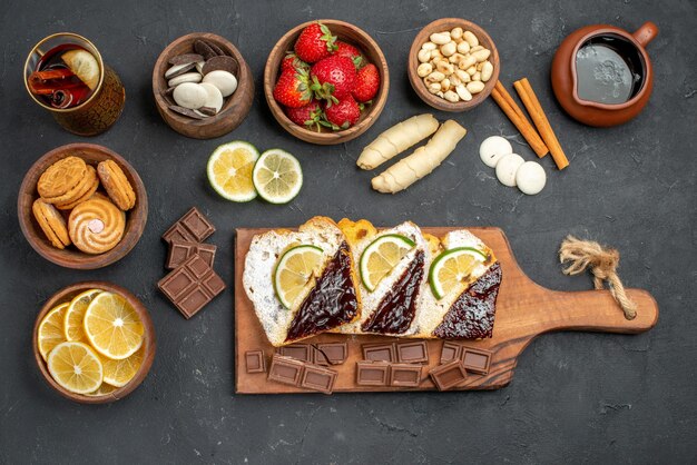 Fette di torta gustosa vista dall'alto con cioccolato e frutta sulla scrivania scura