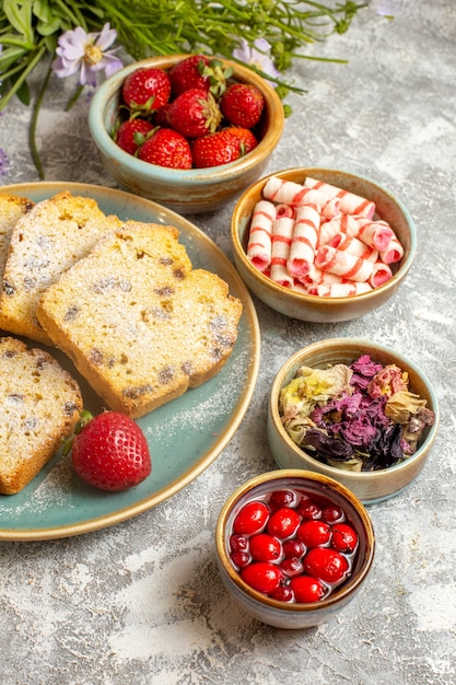 Fette di torta gustosa vista frontale con fragole su torta dolce torta di frutta superficie leggera