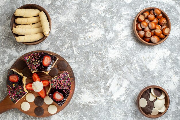 Fette di torta vista dall'alto con biscotti e dolci sulla superficie bianca