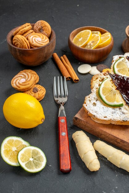 Fette di torta vista frontale con biscotti e cioccolato su sfondo scuro