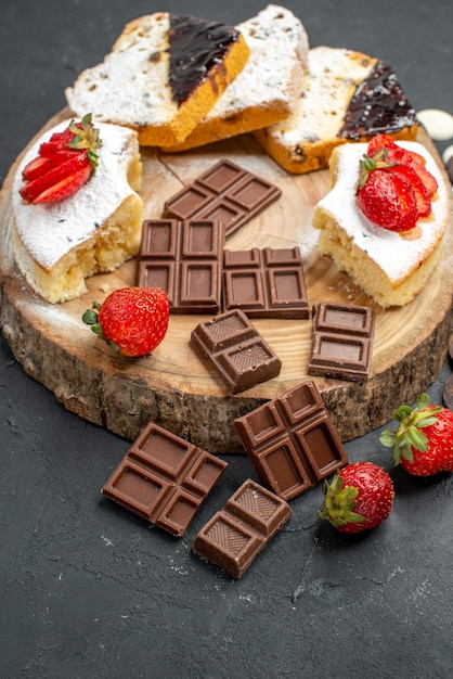 Fette di torta vista mezza superiore con barrette di cioccolato e biscotti su sfondo scuro