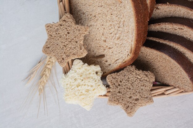 Fette di vari tipi di pane fresco su sfondo di marmo.