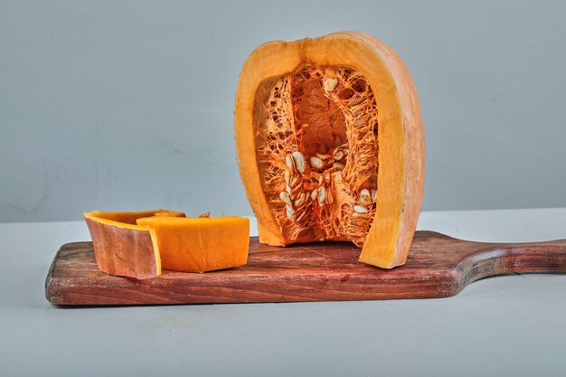 Fette di zucca su tagliere di legno con coltello.