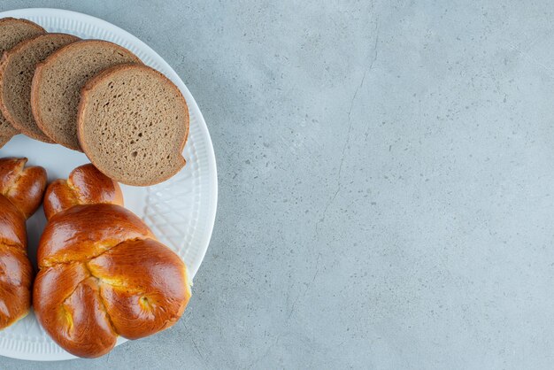 Fette dolci del pane e della pasticceria sul piatto bianco.