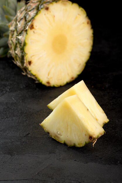 Fette dolci succose mature fresche fresche dell'ananas isolate sul pavimento grigio