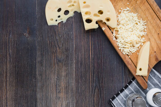 Fette e formaggio grattugiato di maasdam su tavola di legno sopra la scrivania nera