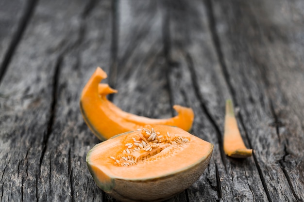 Fette e melone del cantalupo diviso a metà su una vecchia tavola esposta all&#39;aria