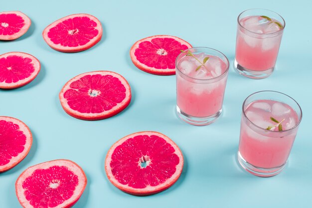 Fette fresche di pompelmo maturo e succo freddo su sfondo blu