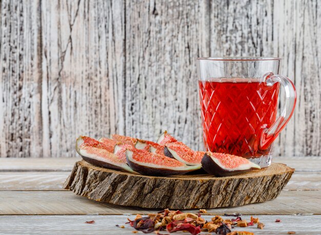 Fichi a fette con tè, erbe secche su un pezzo di legno su legno,