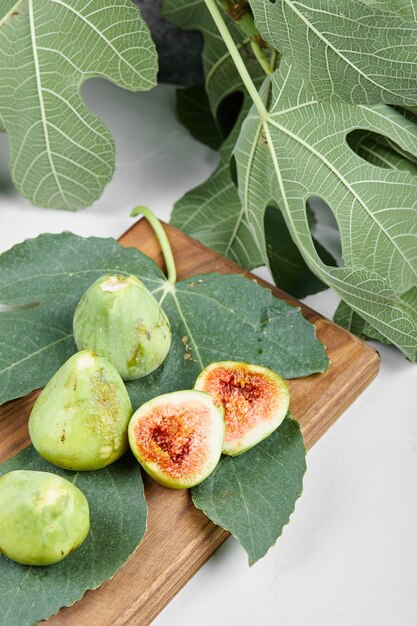 Fichi con foglie verdi su un piatto di legno.