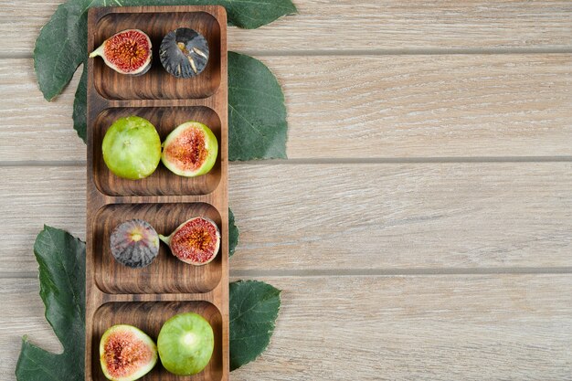 Fichi con foglie verdi su un piatto di legno.