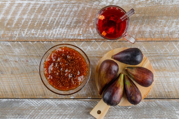 Fichi con una tazza di tè, marmellata di fichi vista dall'alto su legno e tagliere