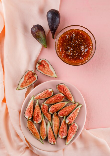 Fichi in un piatto con marmellata di fichi vista dall'alto su rosa e tessuto