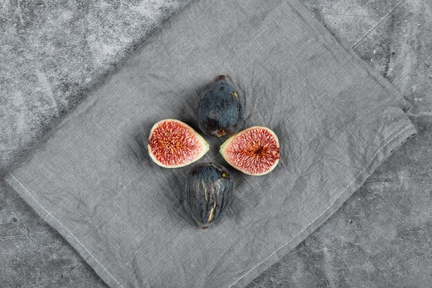 Fichi neri maturi su uno sfondo di marmo con una tovaglia grigia. Foto di alta qualità