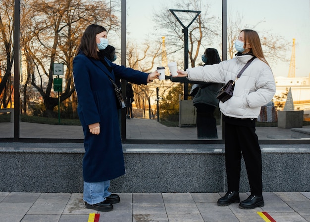 Fidanzate che si incontrano al caffè mentre indossano maschere