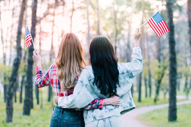 Fidanzate con piccole bandiere americane che abbracciano all&#39;aperto