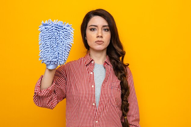 Fiduciosa donna abbastanza caucasica più pulita che tiene in mano un guanto di pulizia in microfibra e guarda