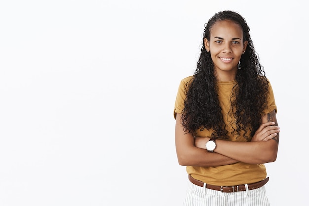 Fiduciosa giovane donna afroamericana sorridente con le braccia incrociate alla ricerca determinata