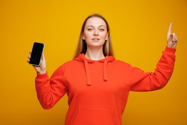 Fiduciosa giovane donna bionda tenendo il telefono cellulare rivolto verso l'alto