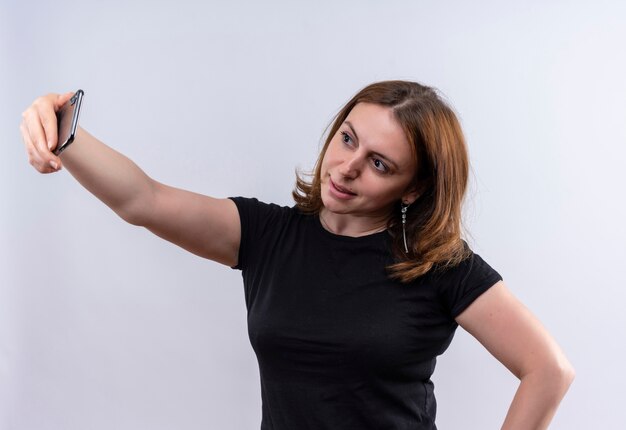 Fiduciosa giovane donna casual prendendo selfie su uno spazio bianco isolato