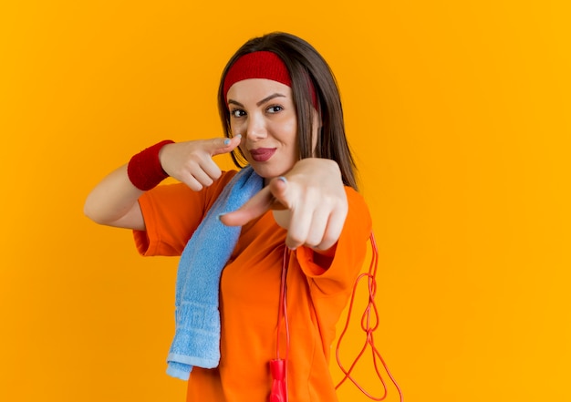 Fiduciosa giovane donna sportiva che indossa la fascia e braccialetti in piedi in vista di profilo con un asciugamano