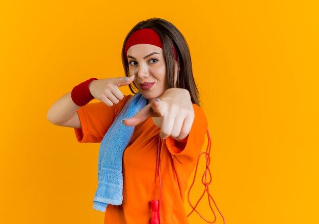 Fiduciosa giovane donna sportiva che indossa la fascia e braccialetti in piedi in vista di profilo con un asciugamano