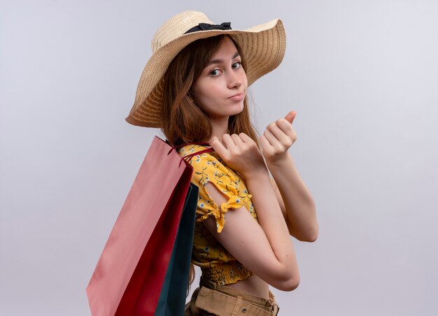 Fiduciosa giovane ragazza che indossa il cappello tenendo i sacchetti di carta in piedi in vista di profilo su uno spazio bianco isolato