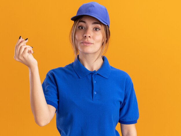 Fiduciosa giovane ragazza graziosa di consegna in segno uniforme della mano dei soldi di gesti sull'arancia