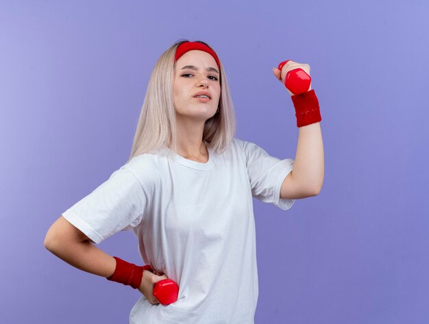 Fiduciosa giovane ragazza sportiva caucasica con le parentesi graffe che indossa la fascia