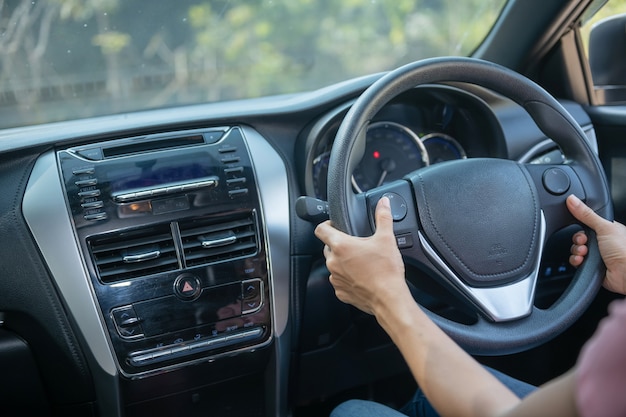 Fiducioso e bello. Vista posteriore della giovane donna attraente in abbigliamento casual guardando sopra la sua spalla durante la guida di un'auto. ragazza che tiene la mano sul volante per gestire l'auto, concetto di sicurezza.