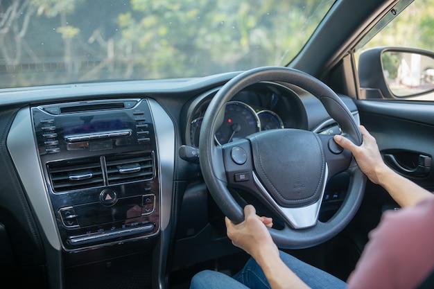 Fiducioso e bello. Vista posteriore della giovane donna attraente in abbigliamento casual guardando sopra la sua spalla durante la guida di un'auto. ragazza che tiene la mano sul volante per gestire l'auto, concetto di sicurezza.