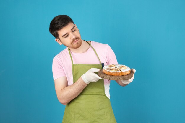 Fiducioso giovane azienda torta fatta in casa e guardandola.