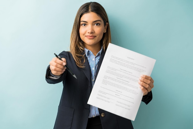 Fiducioso giovane professionista femminile con contratto e penna su sfondo colorato