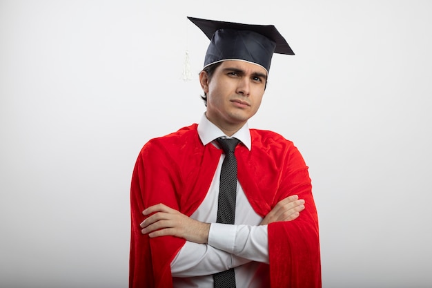 Fiducioso giovane supereroe ragazzo che guarda l'obbiettivo indossando cravatta e cappello laureato che attraversano le mani