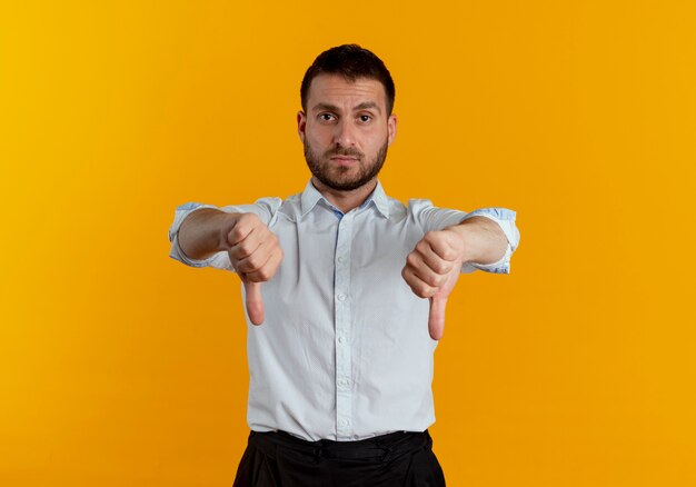 Fiducioso uomo bello pollice in giù due mani isolate sulla parete arancione