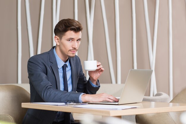 Fiducioso uomo bere caffè e lavora in caffè