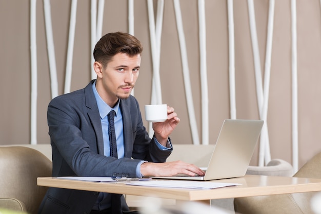 Fiducioso uomo bere caffè e lavora in caffè