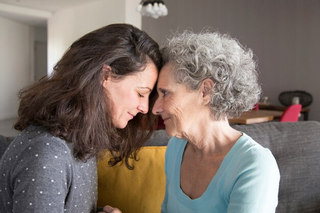 Figlia adulta e madre anziana toccando la fronte