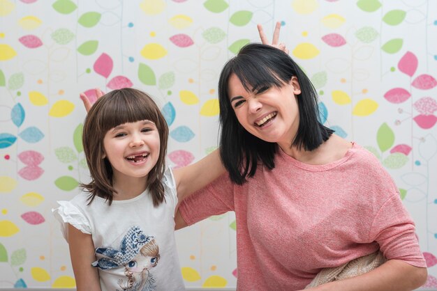 Figlia allegra e madre facendo corna con le dita