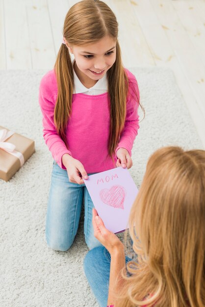 Figlia carina dando biglietto di auguri alla madre