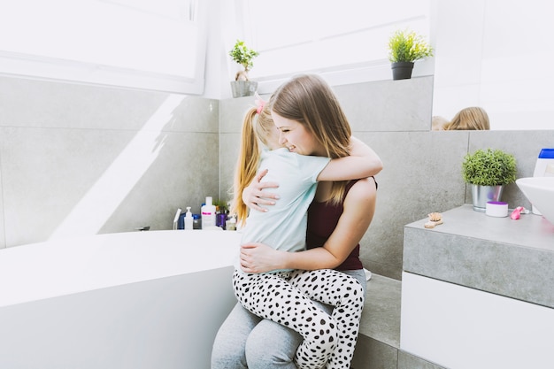 Figlia che abbraccia la madre in bagno