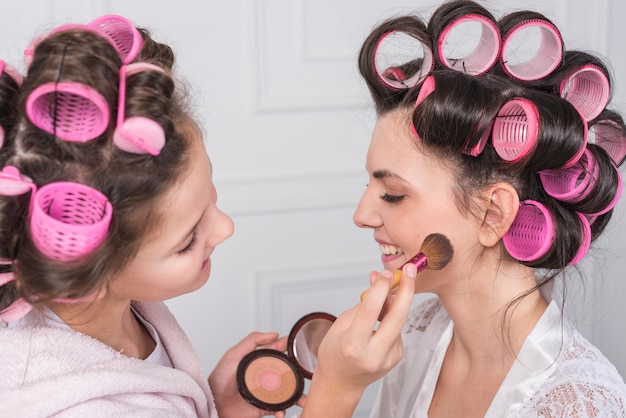 Figlia che mette la polvere sulla guancia delle madri